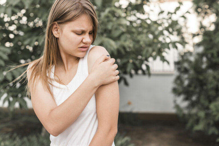 Frau mit Schmerzen im Schulterbereich draußen